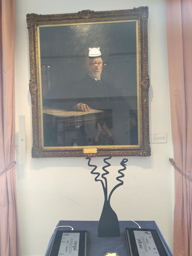 Oil painting with stuck on pussy hat (from the anti trump protests the first time round) and some tablets and a wooden plant shape on a table