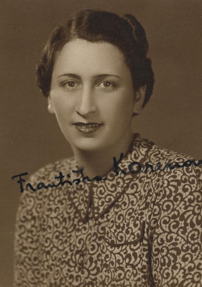 Vintage portrait of a woman with short, styled hair, wearing a patterned blouse. The woman is smiling slightly