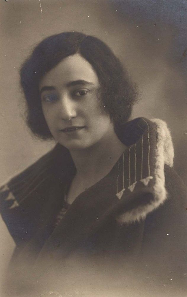 Vintage portrait of a woman with bobbed hair, wearing a dark coat with a fur collar, providing a classic representation of early 20th-century fashion.