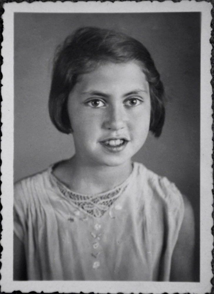 Vintage black and white portrait of a young girl with an earnest expression, wearing an embellished blouse.