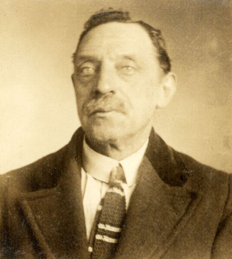 Vintage portrait of an older man wearing a suit and tie, looking directly at the camera with a serious expression.