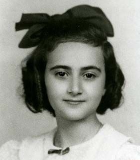 A black and white portrait of Ayoung girl, smiling at the camera, with a bow in her hair.