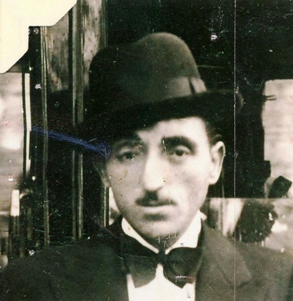 A vintage black and white photo of a man wearing a hat and bow tie.