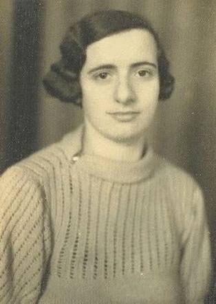 A portrait photo of a woman in a sweater. She has wavy hair reaching to her ears.