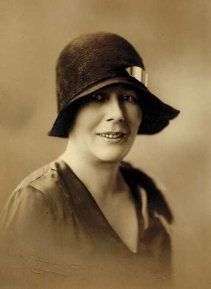 Vintage portrait of a smiling woman wearing a cloche hat and a modest blouse.