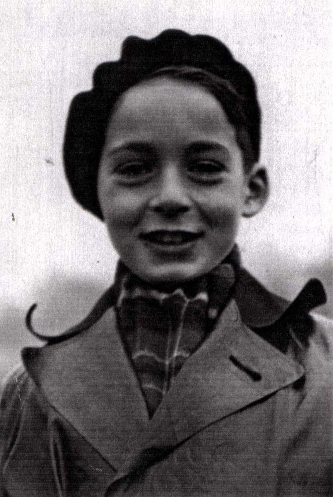 Black and white portrait of a smiling child wearing a beret and a collared coat.