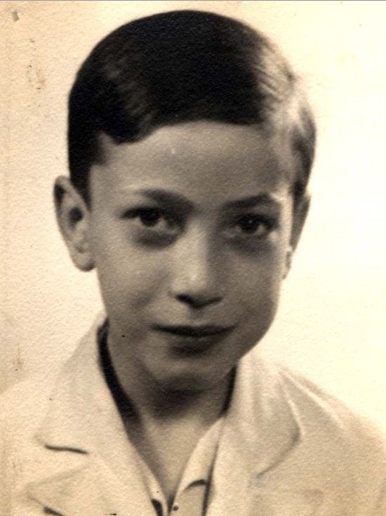 Old portrait of a young boy dressed in a light-colored shirt and has a soft smile. 