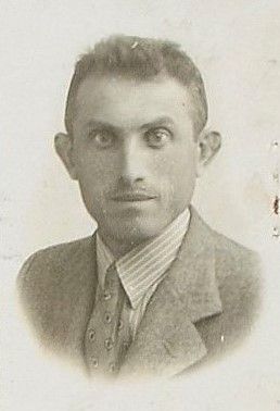 Black and white portrait of a man wearing a suit with a striped sirt and a tie.