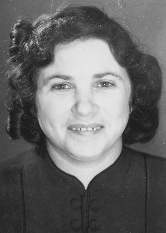 Black and white portrait of a woman smiling with curled hair.