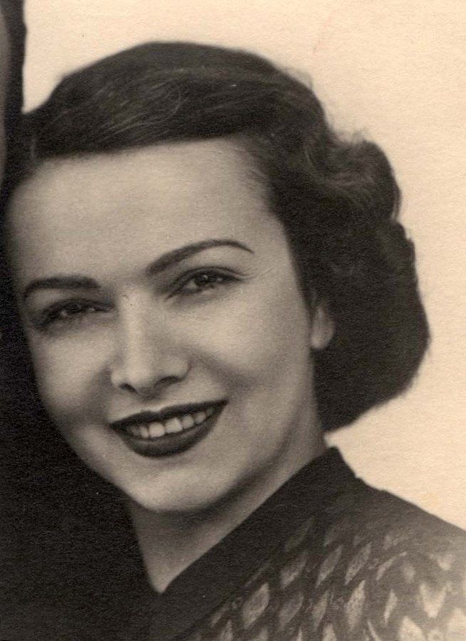 Vintage black and white portrait of a smiling woman with wavy hair, wearing a patterned top.