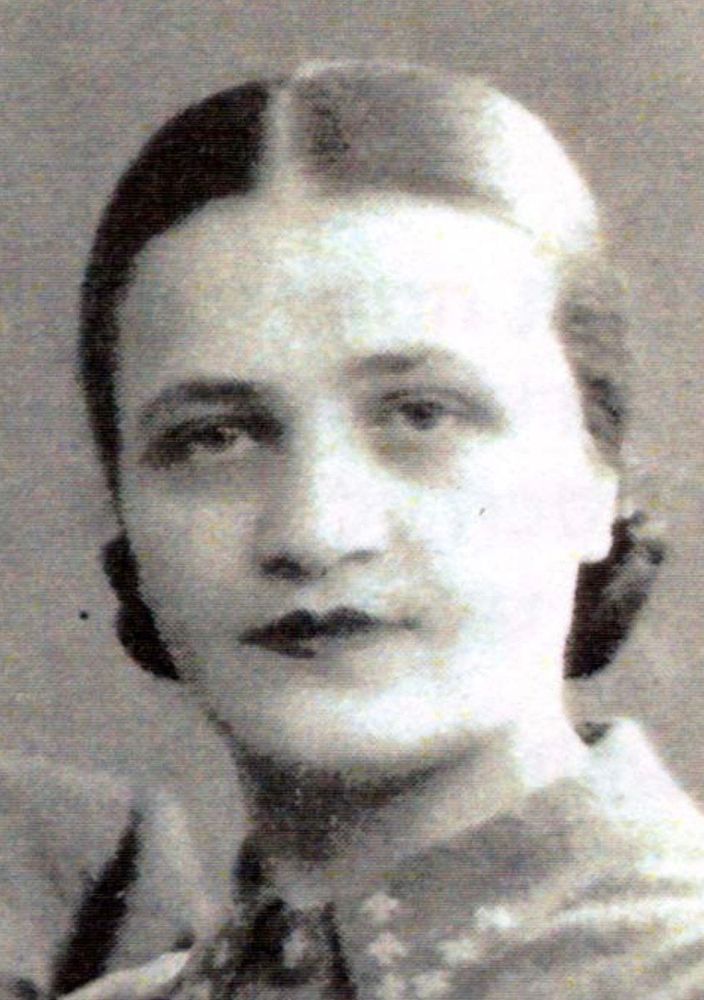 Vintage black-and-white photo of a woman with a middle-parted hairstyle, wearing earrings and a patterned outfit.