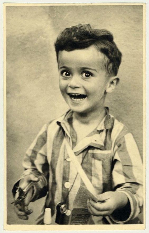 Vintage black-and-white studio portrait of a young boy smiling broadly