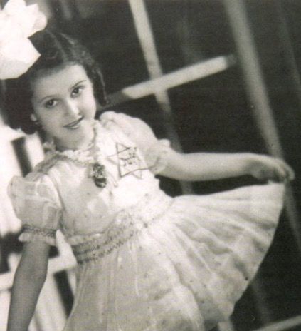 A young dancer in a vintage costume with a Star of David (marking French Jews during the German occupation of France), posing gracefully in a classical dance stance.