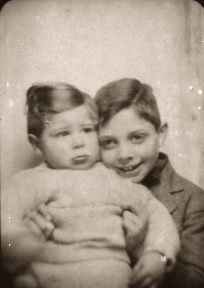 Old sepia photograph of a young boy with an arm around a sibling