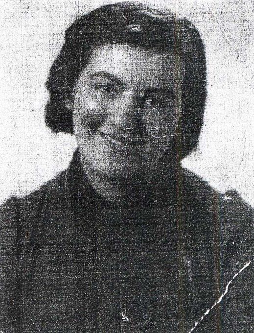 Vintage black and white photo of a smiling girl with hair combed behind her ears, wearing a dark top.
