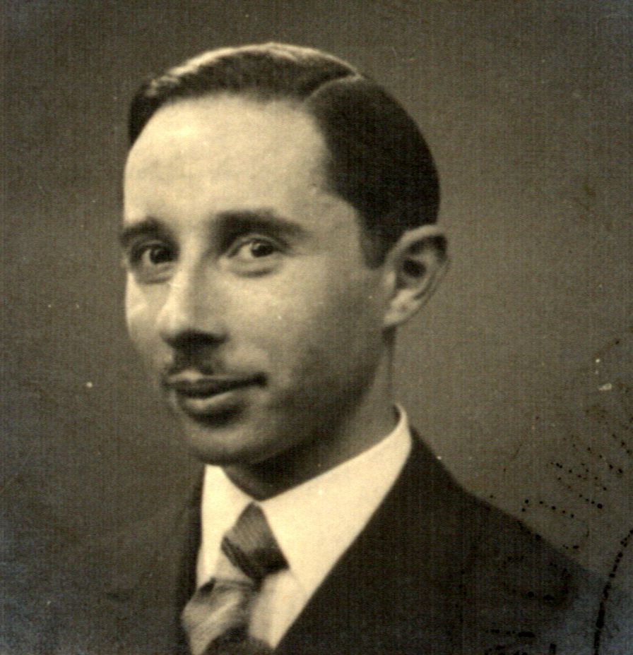 Black and white portrait of a man in a suit and tie, looking slightly to his left with a faint smile.