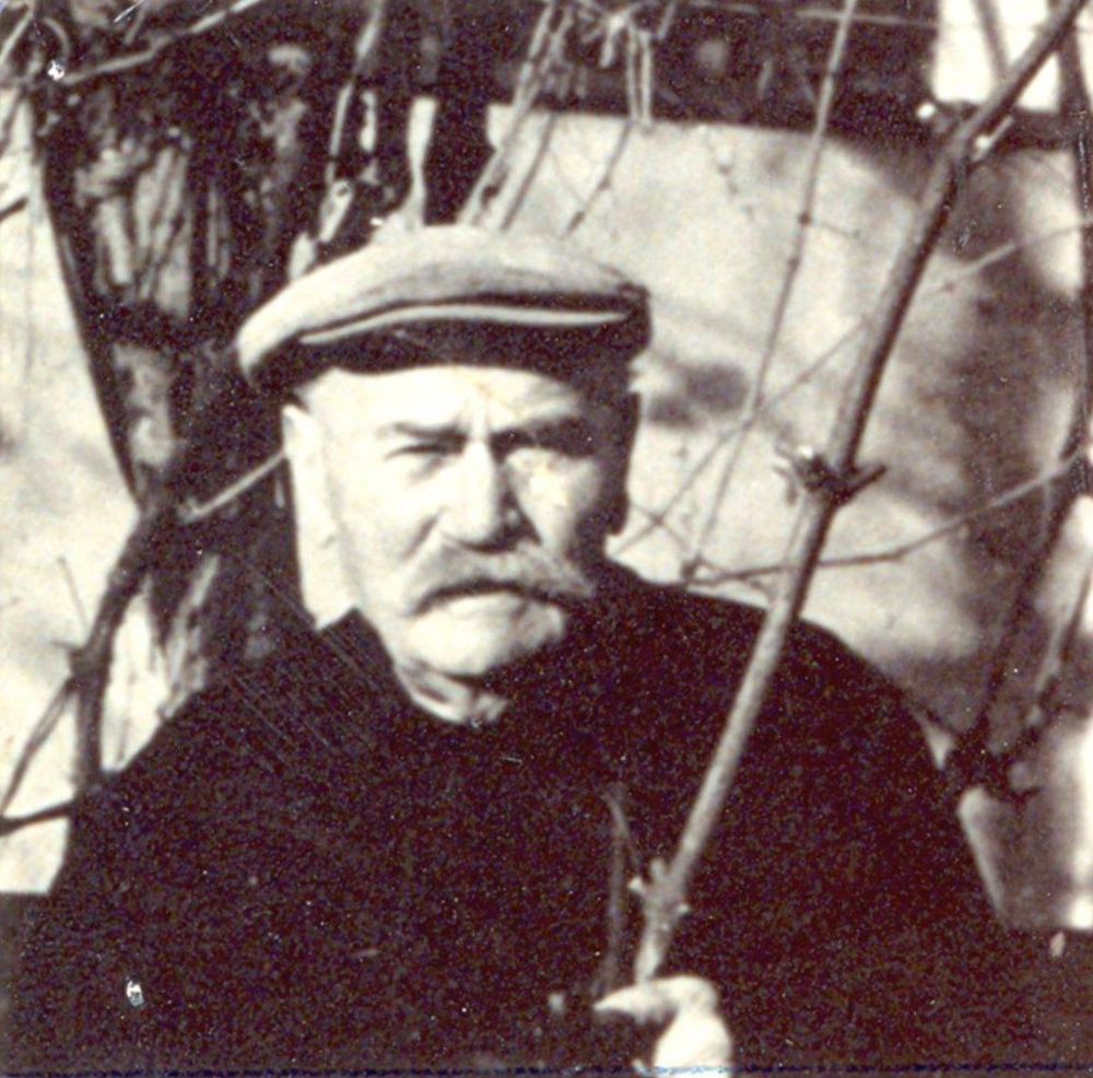 Black and white historical photo of a man wearing a flat cap.