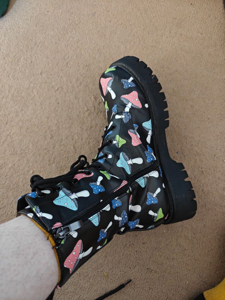 Black, chunky-soled boots. Mid calf length, lots of colourful mushrooms on. 