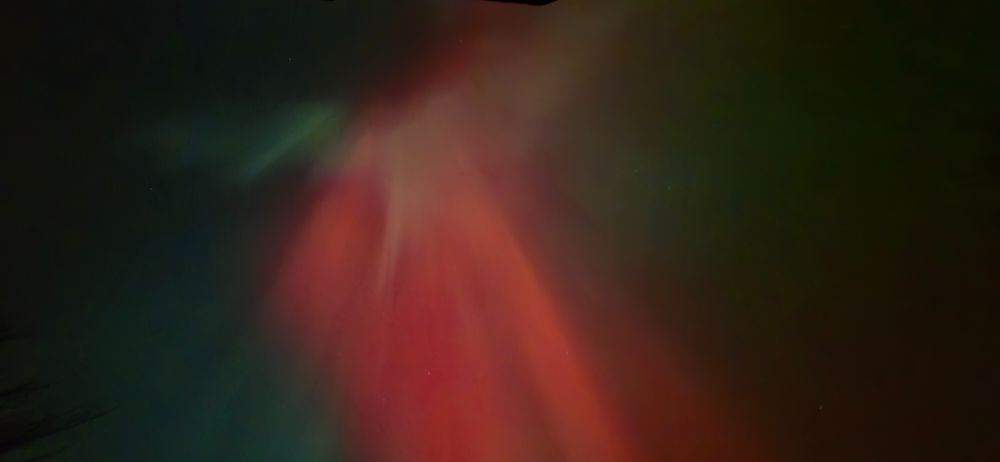 Aurora with green red and some almost white radiating from a central spot almost straight up