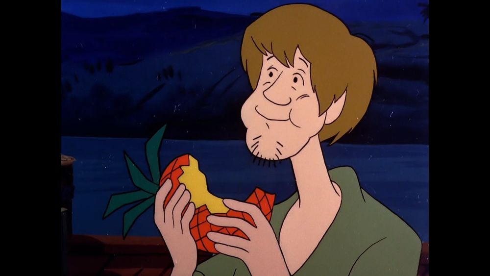 shaggy eating an unpeeled pineapple