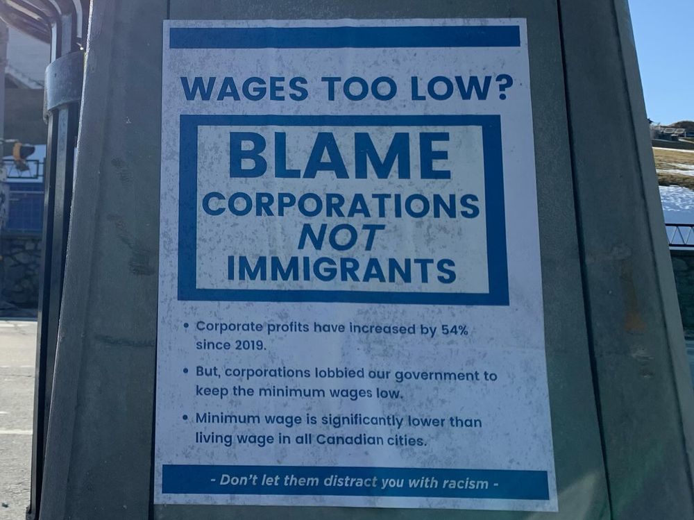 Poster wheatpasted on a street lamp titlted WAGES TOO LOW? BLAME CORPORATIONS NOT IMMIGRANTS & then providing some facts about wage stagnation in Canada.