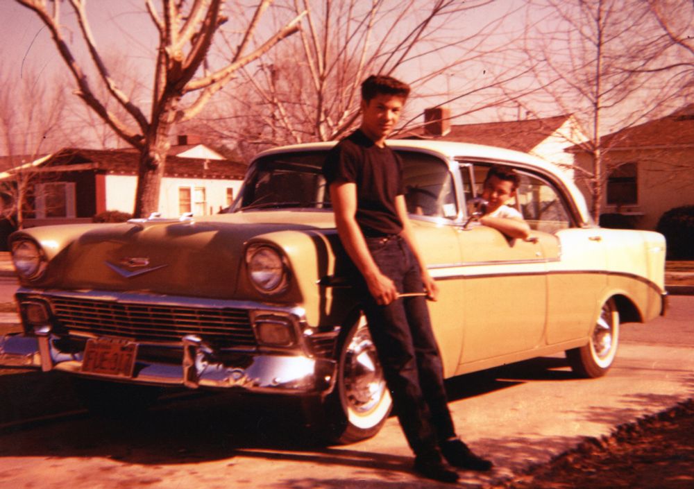 My dad leaning against a '57 Chevy & his twin in the driver's seat.