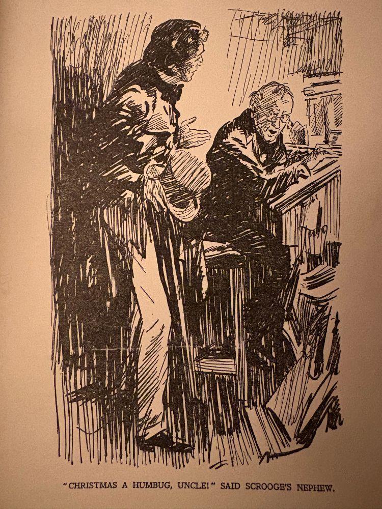 An illustration by Gilbert Wilkinson of Scrooge clad in black sat at his desk and his nephew Fred standing holding a top hat asking 'Christmas, a humbug?!' 