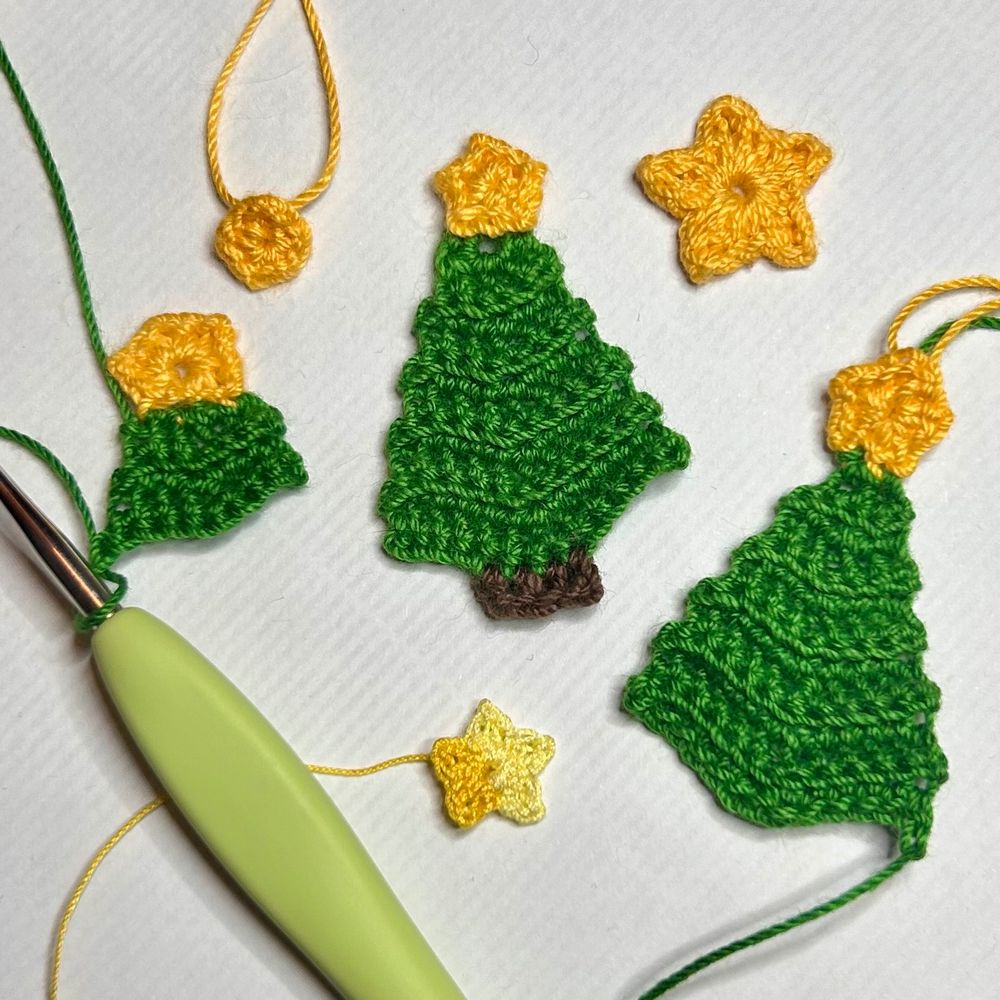 A thread crochet Christmas tree, two partial Christmas trees, three different stars, and a crochet hook.