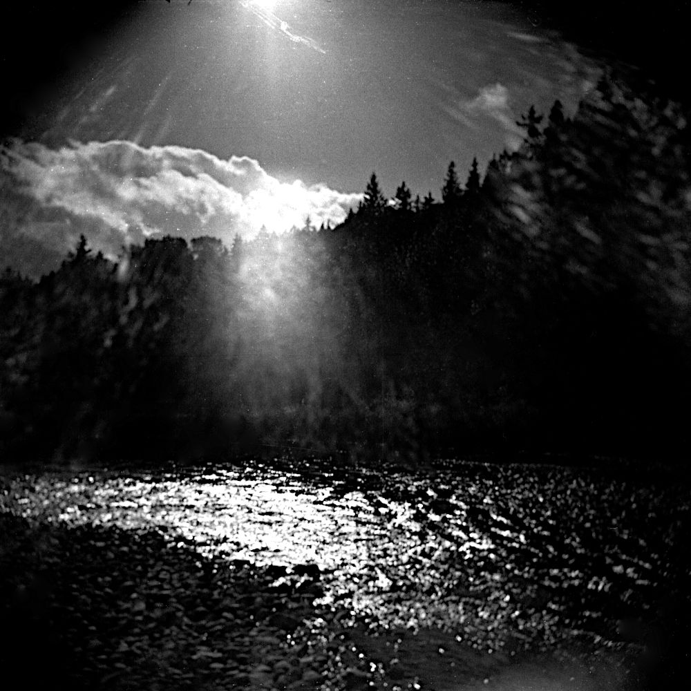 Black and white photo of sun sparkling on the river.