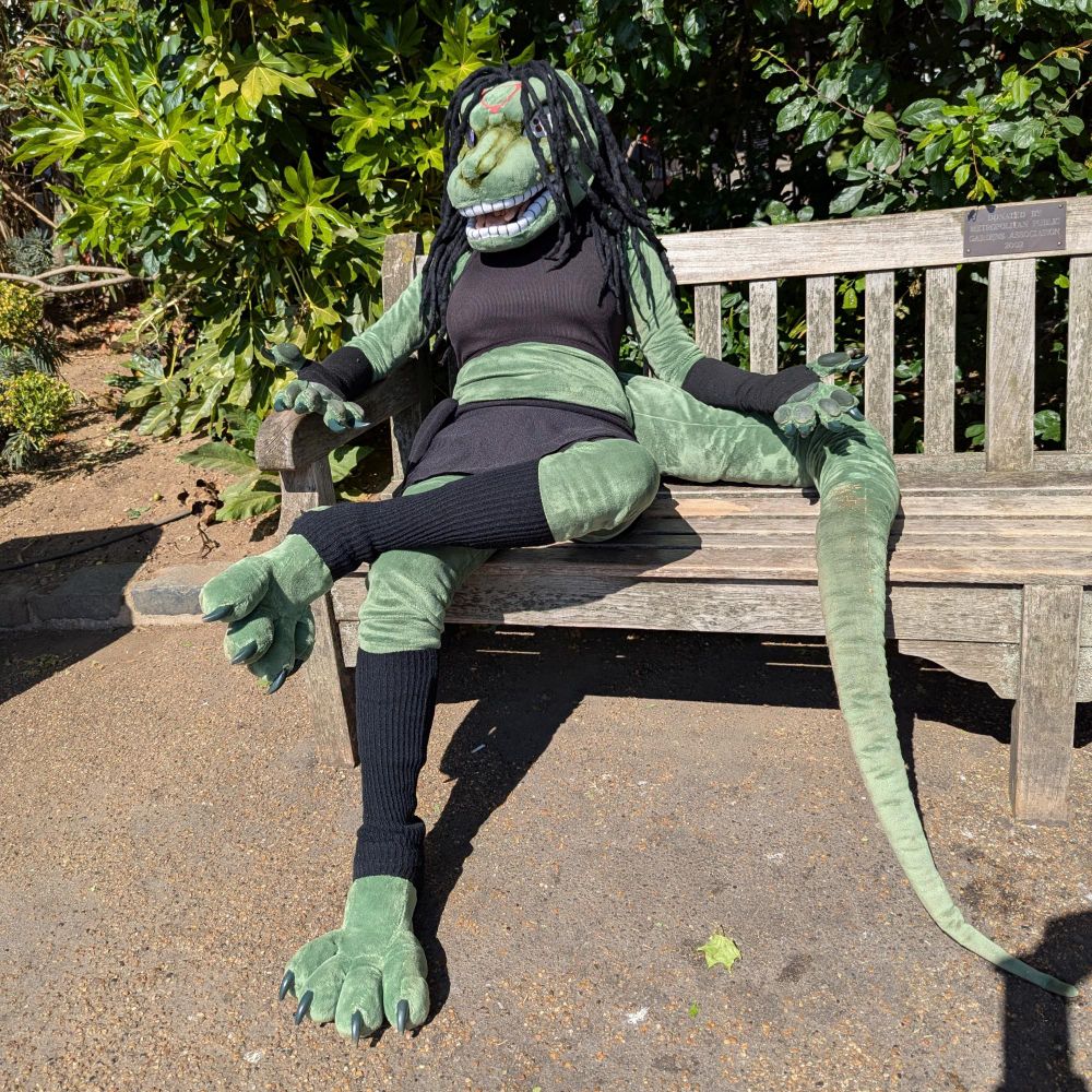 Cosplay fursuit of Envy from Fullmetal Alchemist in their monster/true form, sitting on a park bench.
