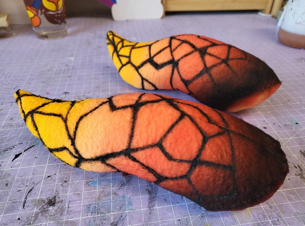 A pair of airbrushed/painted plushy horns for a fursuit head, featuring a crackled 'hot coal' type design.