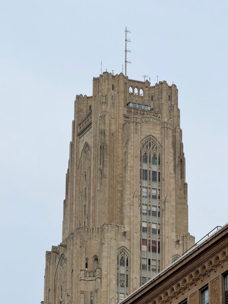Zoomed in view of the top of the Cathedral of Learning at the University of Pittsburgh, a tall building with gothic design language.