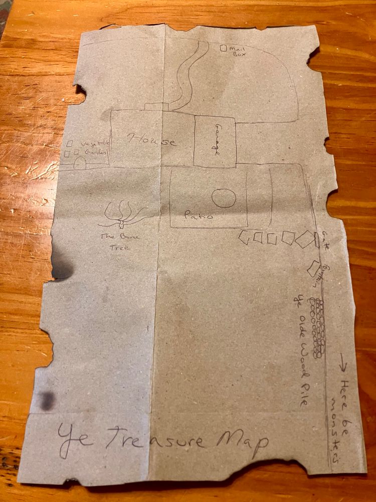 Photo of a brown paper bag treasure map with some landmarks on it, the edges have been singed with fire to look olde.
