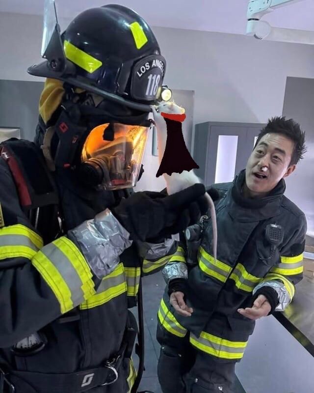 photo of Anirudh in full turnouts holding a white rat in a vampire cape with fangs up to his helment, Kenny is in the background looking at them