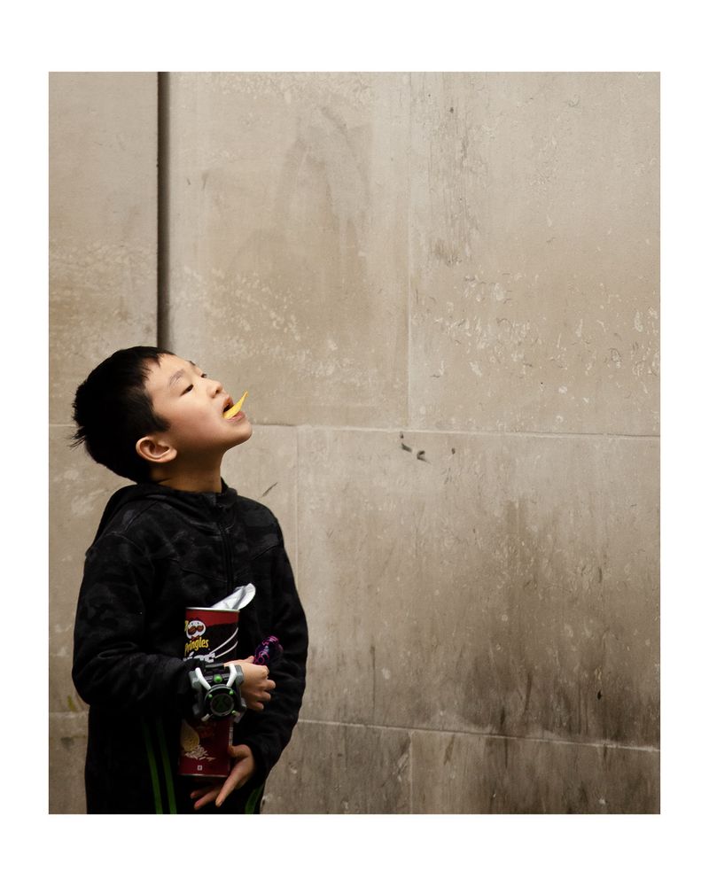 London street photo of a lad who loves his pringles. 