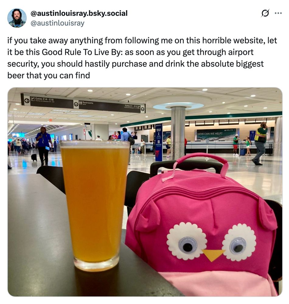 a big beer at the airport in 2024 next to a pink owl suitcase