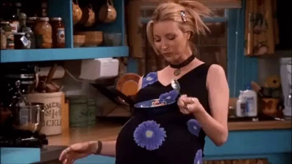 a pregnant woman in a floral dress is eating cereal