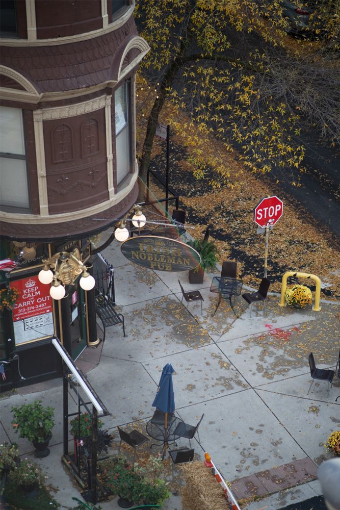The original, raw, unedited photo used as a base for the fall illustrations in the above post. This features an aerial view of an Irish pub on the corner of a street in Chicago. Orange leaves are scattered across the ground. The colors are a bit dull.