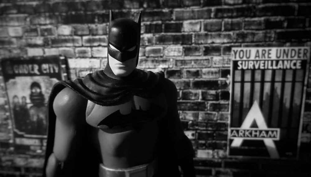 A classic styled (Matt Wagner - DC Trinity) Batman figure stands in an alleyway in Gotham city, with Arkham City posers on the walls.