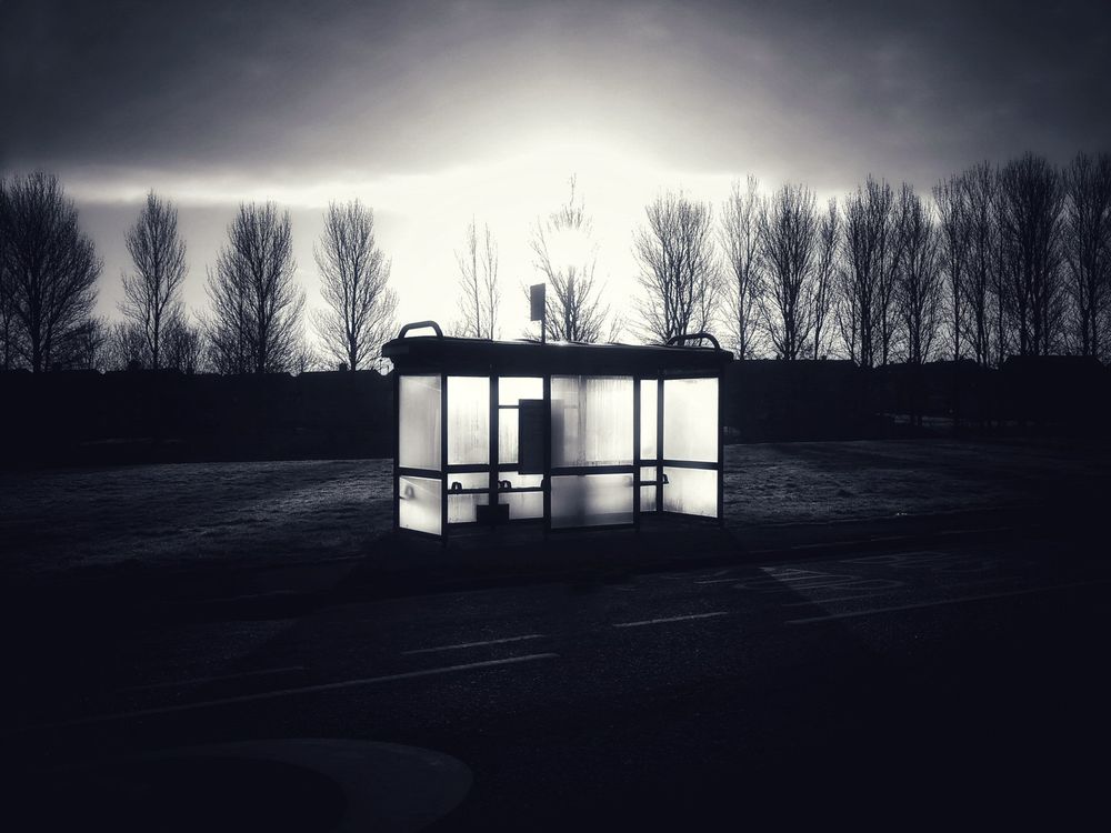 A dramatic sunrise fills a very dirty bus stop with light, reminding us that getting up and going to work is a fucking drag, but sometimes you get to snap a cool pic anyway.