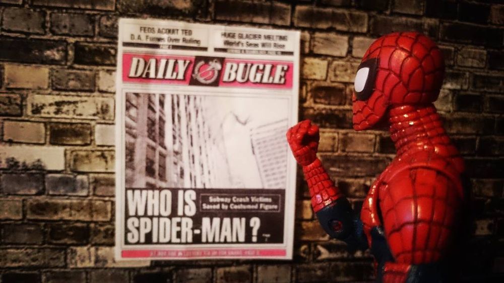A Spider-Man action figure shakes his fist at a Daily Bugle poster - bad press yo.