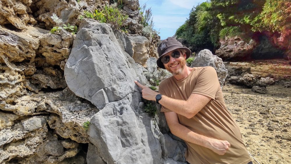 A picture of me pointing to a fossil Porites coral to my right.