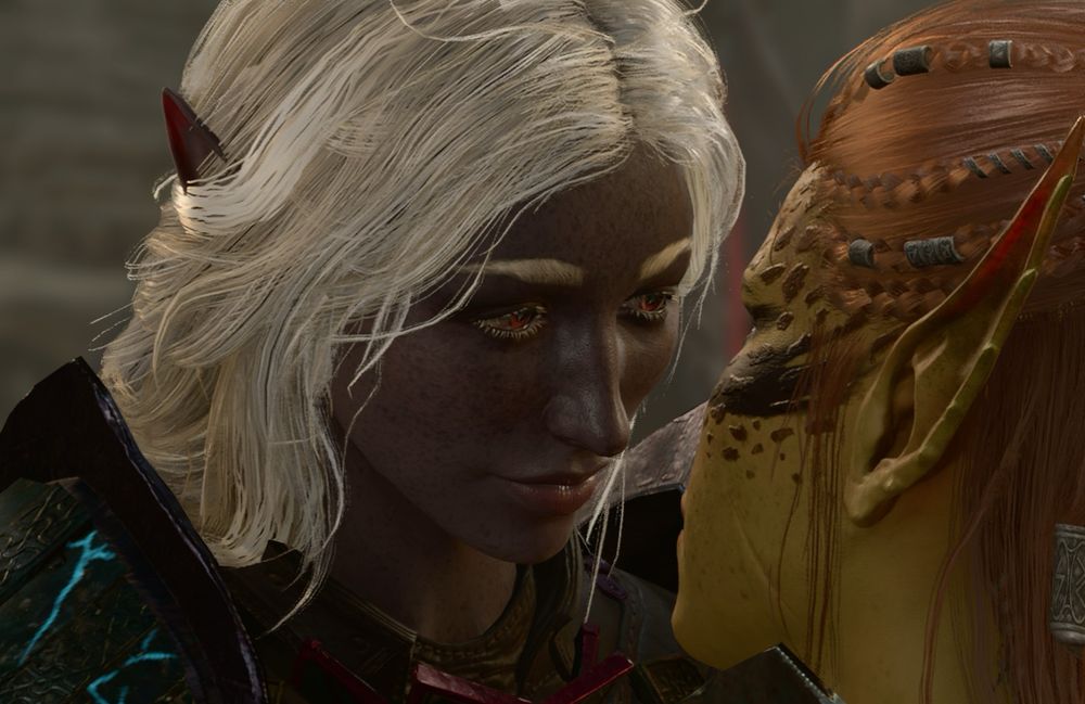 A screenshot from Baldur’s Gate 3 of a young drow woman with freckled purple skin, long white braided hair, and red eyes looking into Lae’zel’s eyes. Lae’zel is a young githyanki woman with yellowish green skin and red hair. 