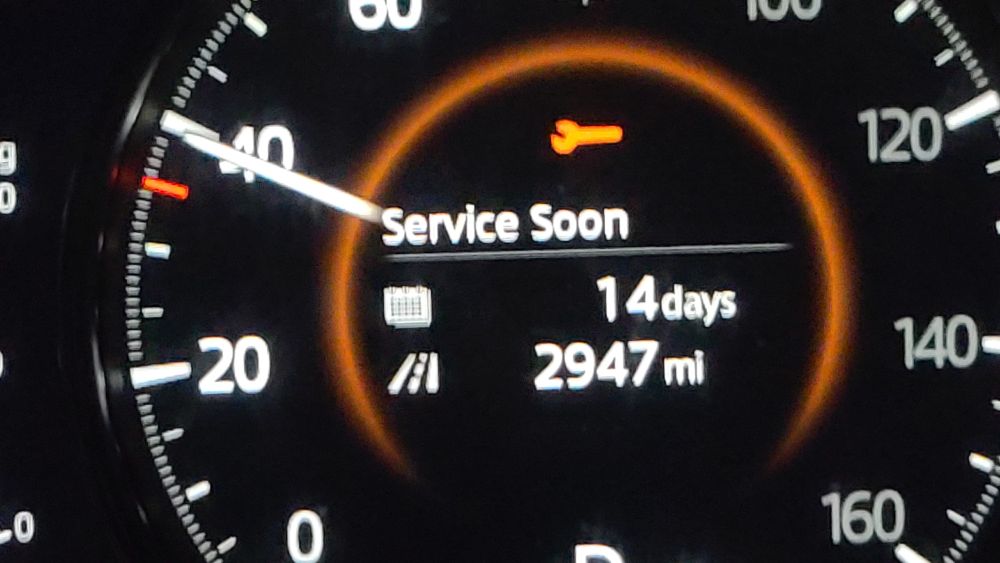 A car speedometer showing "service soon - 14 days - 2947 miles"