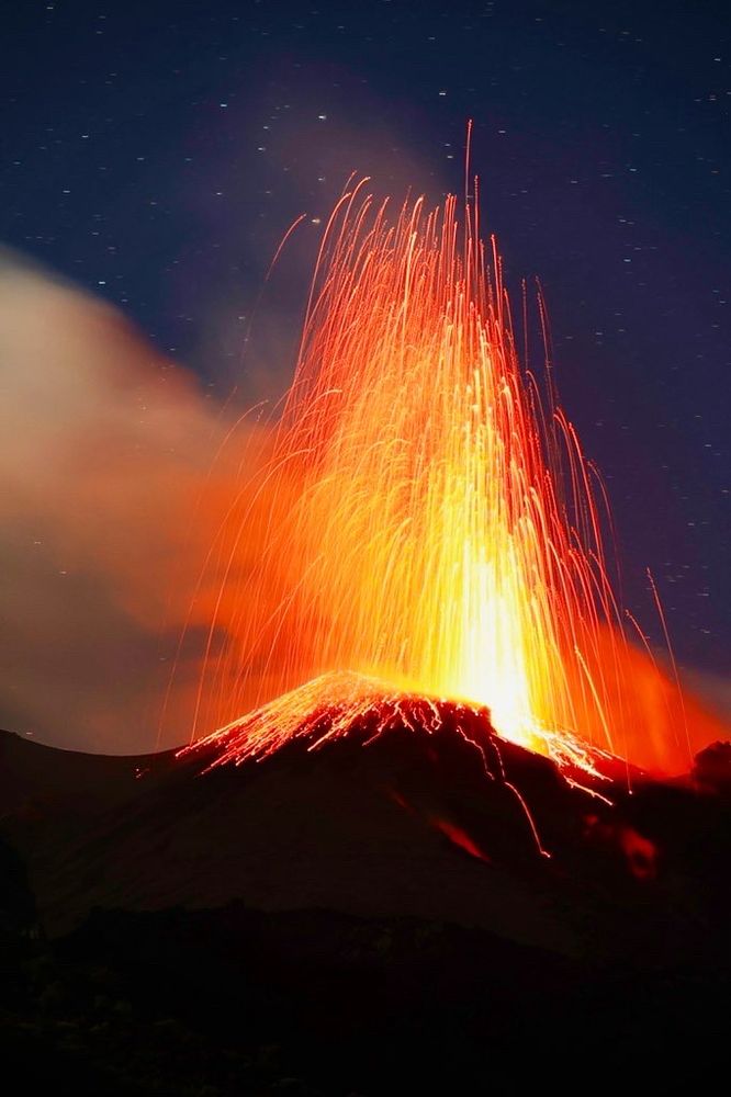 Ein ausbrechender Vulkan, durch die längere Belichtung sieht die Lava aus wie Fäden