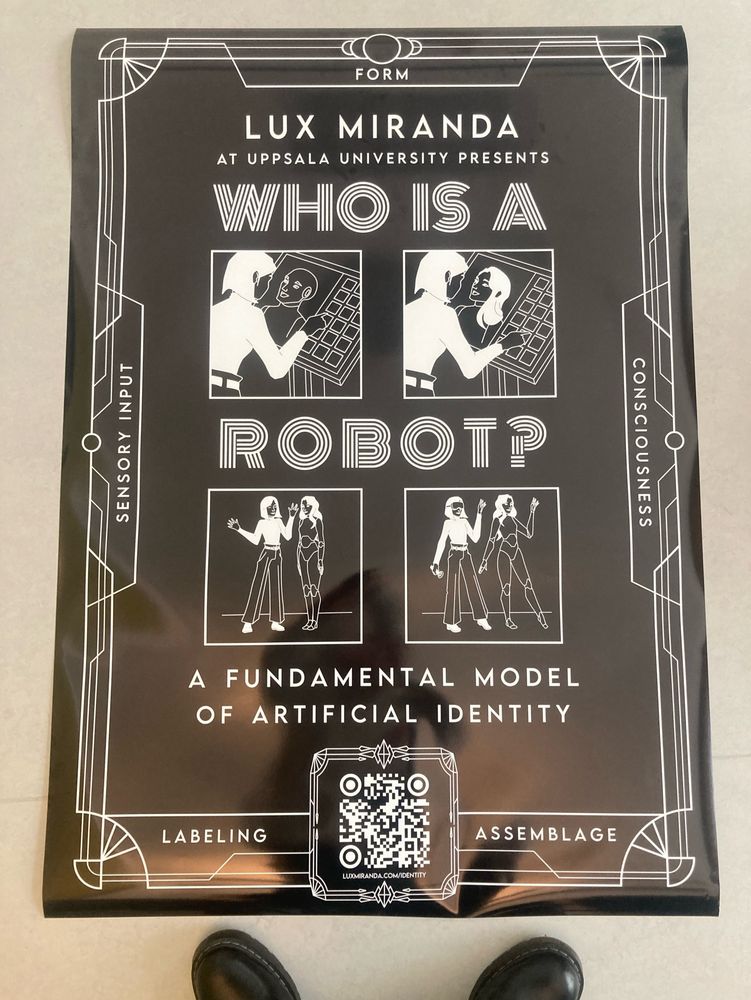 A photo of an black and white art-deco-stylized poster reading “Lux Miranda at Uppsala University presents: WHO IS A ROBOT? A fundamental model of artificial identity.” The poster features four panels of a woman interacting with a robot whose form shifts between androgynous, feminine, digital, physical, and merged with the woman themself. The border is emblazoned with five terms: Form, Sensory input, Consciousness, Labeling, and Assemblage. A QR code links to luxmiranda.com/identity. 