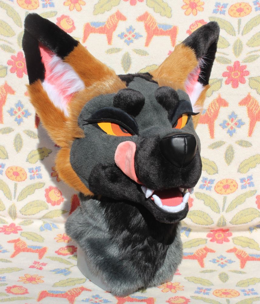 Cross fox fursuit head with the magnetic eyelids on. A magnetic tongue makes it look like she’s licking her lips.