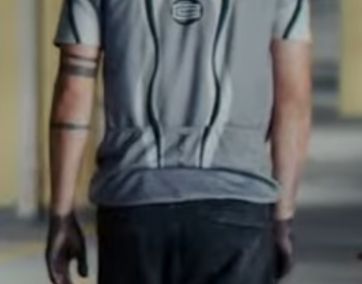 Man wearing a grey cycling jacket from the back showing a distinct C logo on the back