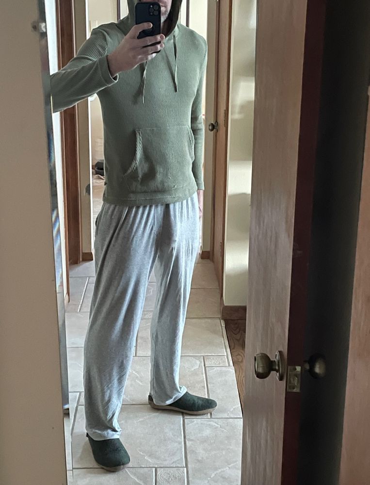 Adult man in gray sweats and waffle hoodie taking a mirror selfie. Face obscured by phone camera.