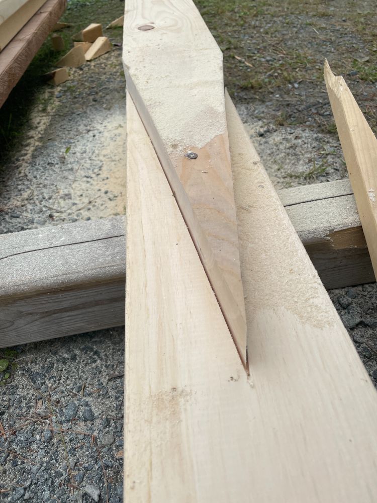 Two boards overlapping, the top board has been cut along the triangle and waster wood removed. The bottom board has been partially cut along the triangle during the first cut.
